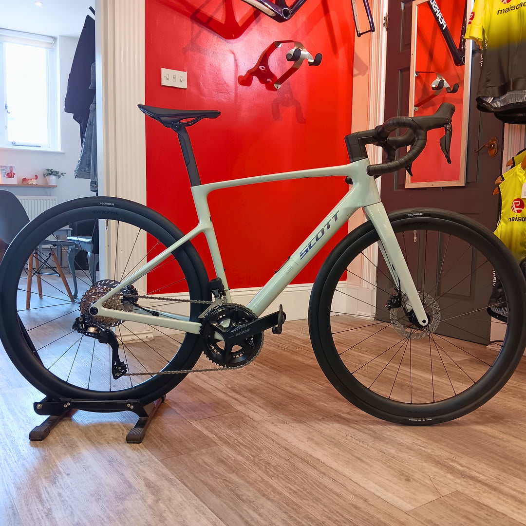 Light blue bicycle on a stand in a room with red walls and various items in the background