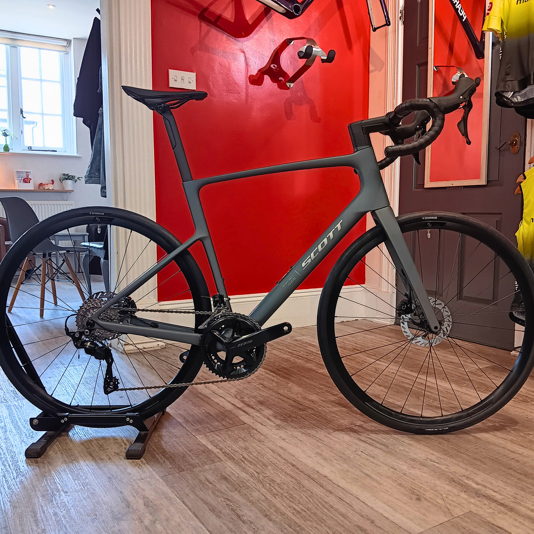 Gray bicycle on a stand in a room with red walls and wooden floors.